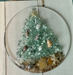 a glass ornament with a christmas tree made out of seashells and starfish