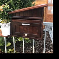 a wooden mailbox sitting on top of a metal rail next to a potted plant