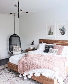 a bedroom with a bed, rugs and pictures on the wall above it is also a hammock chair