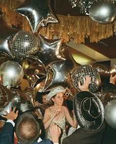 a group of people standing around each other in front of disco balls and streamers