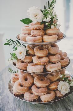 three tiered trays filled with donuts and flowers