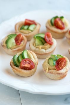 small appetizers with cucumbers and tomatoes are on a white platter