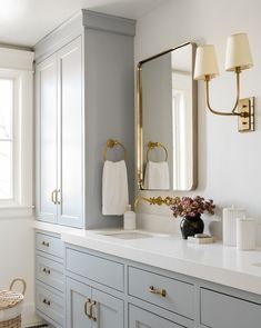 a white bathroom with gray cabinets and gold accents on the mirror above it is an instagram page for pinterest