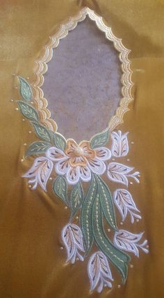 a piece of cloth with flowers and leaves embroidered on the side, sitting on a table