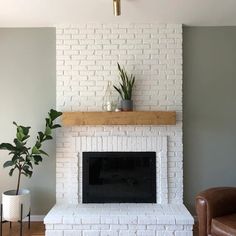 a living room with a white brick fireplace and potted plants on the mantel