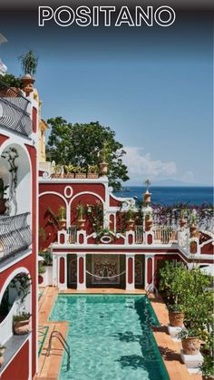 an outdoor swimming pool in front of a red building with the words positanoo above it