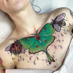 a woman with a green butterfly and ladybug tattoo on her chest is laying down