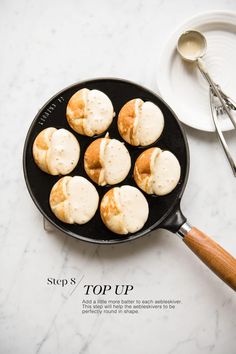 a pan filled with biscuits on top of a table next to a plate and utensils