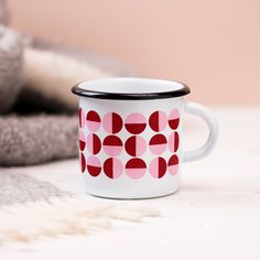 a white and red coffee cup sitting on top of a table