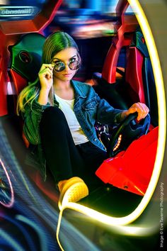 a woman sitting in the driver's seat of a car talking on her cell phone