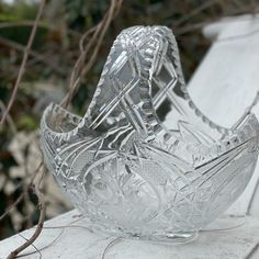 a clear glass bowl sitting on top of a white table next to a tree branch