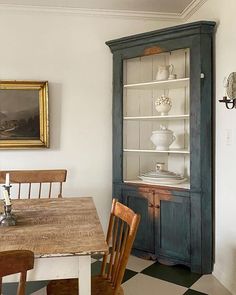 a dining room table and chairs in front of an old china cabinet with glass doors