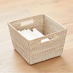 a wicker basket with books in it on the floor