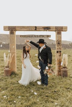 a bride and groom dancing in front of a wooden sign