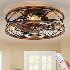 a person holding a remote control in front of a ceiling fan