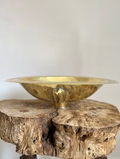 a golden bowl sitting on top of a wooden table next to a piece of wood