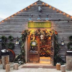 an entrance to a store with lights on the roof and wreaths hanging from it