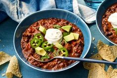 two bowls of chili with avocado, sour cream and tortilla chips