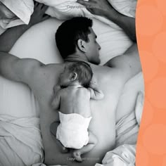 a man laying in bed holding a baby