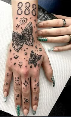 a woman's hand with tattoos on it and butterflies in the middle of her fingers