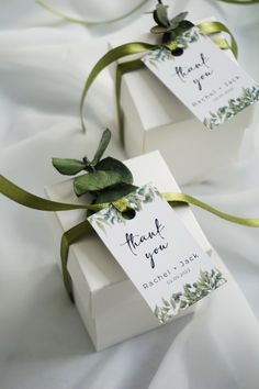 two white boxes with green ribbons tied to them