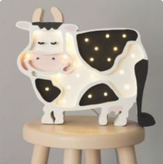 a light up cow sitting on top of a wooden stool