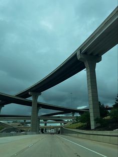 an overpass is seen from the inside of a car's windshield as it travels under a cloudy sky