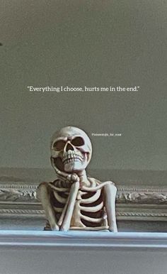 a skeleton sitting in front of a mirror with a quote on the wall above it