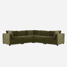 a green sectional couch with two pillows on it's back and one arm facing the camera