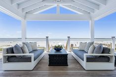 an outdoor living area with couches and tables on the deck next to the ocean