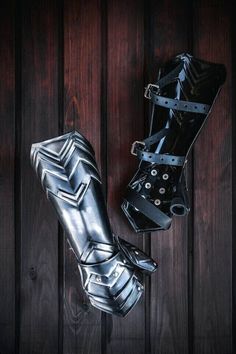 two pairs of black and silver leather boots on top of a wooden floor next to each other