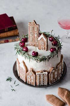 a gingerbread cake decorated with icing and cherries on a plate next to cookies