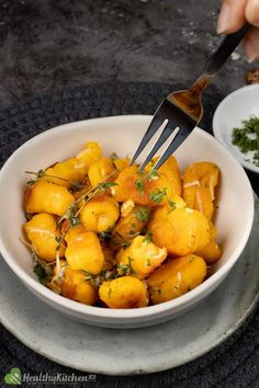 a white bowl filled with fried potatoes and garnished with herbs