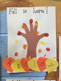 a bulletin board with fall is here written on it and an apple tree in the middle