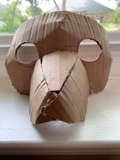 an animal made out of cardboard sitting on top of a window sill