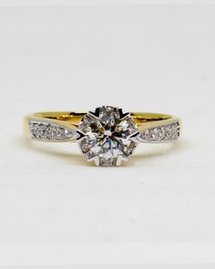 a yellow and white gold engagement ring with a round cut diamond in the center, surrounded by pave diamonds