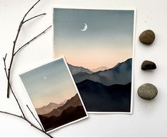 three cards with mountains in the background and two rocks on the ground next to them