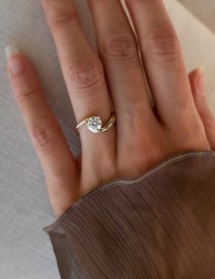 a woman's hand with a diamond ring on top of her left hand,