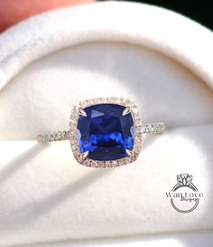 an engagement ring with a cushion cut blue sapphire surrounded by pave diamond halos