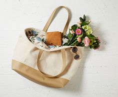 a tote bag sitting on top of a wooden table next to a bouquet of flowers