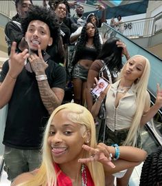 the group of people are posing together in front of an escalator with their hands up