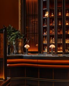 the bar has many bottles on it and is lit by lights in the dark room