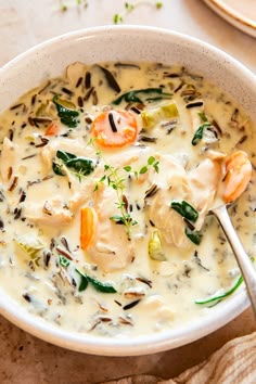 a bowl of soup with shrimp, carrots and spinach in it on a table