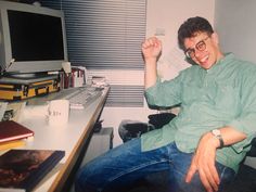 a man sitting in front of a desk with a computer monitor and keyboard on it