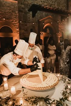 two chefs are cutting into a large cake