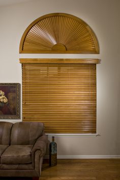 a living room with a brown couch and wooden blinds