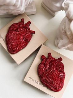 two red sequinized heart brooches sitting on top of a white table