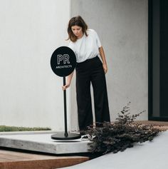 a woman standing next to a black sign