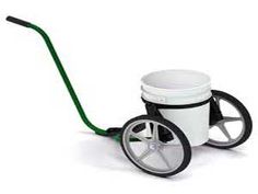 a white coffee cup sitting on top of a green wheelbarrow with a handle