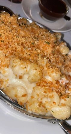 macaroni and cheese covered with parmesan on a white plate next to silverware